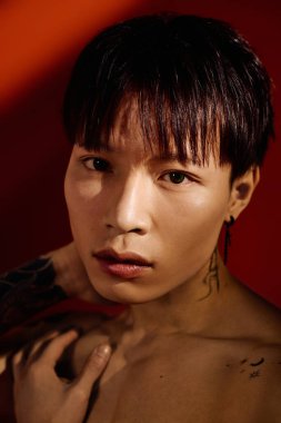 Dövmeleri olan Asyalı genç bir adam çarpıcı bir ifadeyle şık görünümünü sergiliyor..