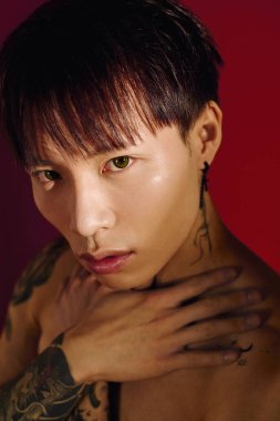 Dövmeleri olan genç yakışıklı bir adam sanatsal bir ortamda çarpıcı bir görünüm sergiliyor..