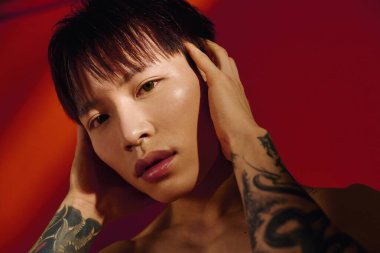 Şık bir Asyalı genç adam canlı bir günbatımı arkaplanına güvenle poz veriyor..