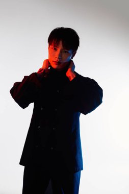 Kendine güvenen genç bir adam tasmasını ayarlar. Tarzı ve cazibesini en düşük arkaplana göre ayarlar..