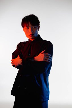 Yakışıklı Asyalı bir adam kendine güvenerek duruyor, etkileyici ışıklandırma efektleri olan eşsiz bir stili benimsiyor..