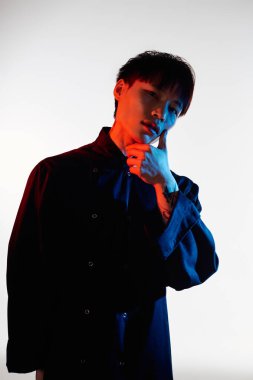 Şık bir Asyalı genç adam kendine güvenerek derin düşüncelere dalmış ve modasını sergiliyor..