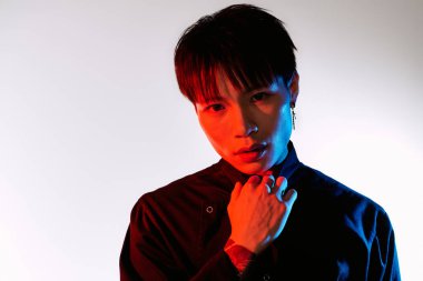 Havalı Asyalı adam kendine güvenerek renkli bir arkaplanda poz veriyor, çekiciliğini sergiliyor..