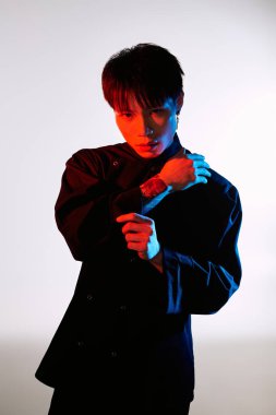 Yakışıklı, genç Asyalı bir adam büyüleyici bir ışığın ortasında poz verirken eşsiz tarzını sergiliyor..