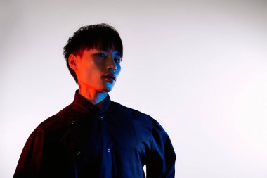 Yakışıklı Asyalı bir adam canlı renklere karşı kendine güvenen bir ifadeyle tarzını sergiliyor..