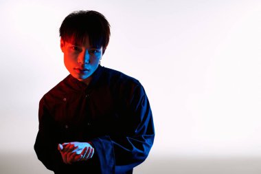 Genç, yakışıklı Asyalı bir adam çarpıcı bir şekilde şık bir şekilde poz veriyor..