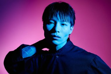 Yakışıklı Asyalı adam etkileyici bir ifadeyle şık görünümünü sergiliyor dramatik ışıklandırmada.