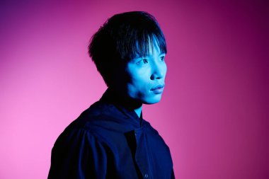 Yakışıklı genç bir Asyalı şık poz veriyor canlı, renkli bir arkaplana karşı.