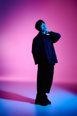 Genç bir Asyalı modern modayı canlı pembe ve mavi bir arka plana karşı modelliyor..