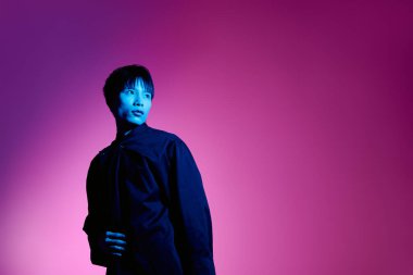 Şık bir Asyalı adam renkli bir ışıkla ışıldar, büyüleyici ve kendine güvenlidir..