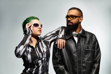 Modern bir stüdyo ortamında şık genç bir çift eşsiz kıyafetlerini ve güneş gözlüklerini sergiliyor..
