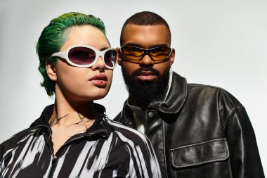 Modaya uygun genç bir çift birlikte poz verirken benzersiz güneş gözlüğü tarzlarını sergiliyor..