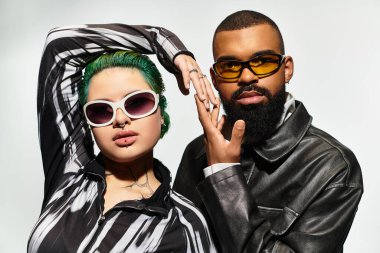 Şık görünümlü genç bir çift, güneş gözlüklü modaya uygun kıyafetler giyer..