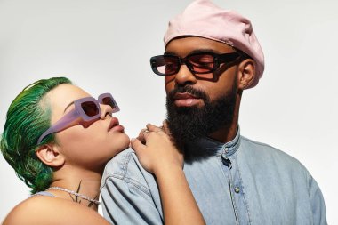 Genç çift şık güneş gözlükleriyle birlikte poz veriyor, moda ve çeşitliliklerini vurguluyorlar..