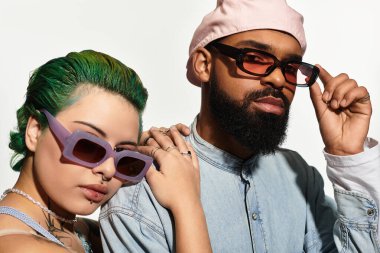 Çok kültürlü bir çift, modaya uygun bir stüdyoda özgün tarzlarını vurgulayarak güven içinde poz veriyor..