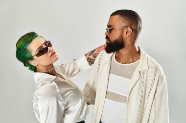 Genç bir çift modern bir stüdyoda güven içinde poz verirken şık kıyafetlerini sergiliyor..