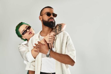 Çok kültürlü genç bir çift modern bir stüdyoda güneş gözlüğü takarak şık bir anın tadını çıkarıyor..