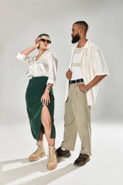 Genç, çok kültürlü bir çift, çeşitliliği ve moda eğilimlerini kutlamak için şık pozlar veriyor..