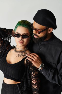 Moda çifti modern bir stüdyoda birlikte poz verirken şık kıyafetler sergiliyor..