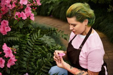 Çiçekleri beslemekle meşgul olan genç bir kadın, sera bahçesinin güzelliğini keşfeder..