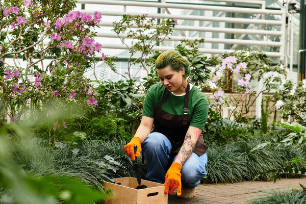 In a lively greenhouse, a young woman kneels to nurture her plants with loving care.