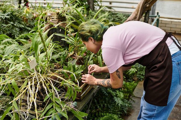 Молодая женщина выращивает цветущие растения в яркой оранжерее, демонстрируя свою страсть к садоводству.