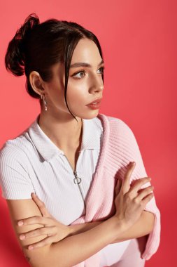 Çekici özellikleri olan genç bir kadın, kollarını kavuşturmuş, güzel ve güzel bir şekilde duruyor..