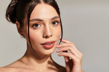 Büyüleyici özellikleri olan bir kadın, sessiz bir arka plana karşı zarif bir şekilde durarak güzelliğini ifade eder.