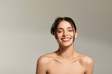 Parlak bir gülüşü olan genç ve güzel bir kadın Yumuşak bir ışıkta dinginliğin tadını çıkarıyor.