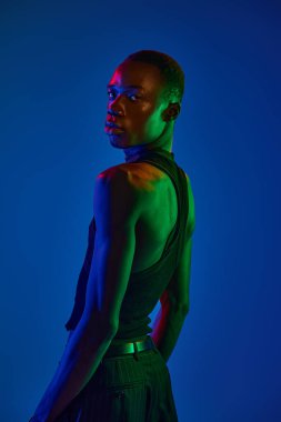 Yakışıklı genç bir adam şık bir şekilde poz veriyor, canlı renklerle aydınlatılıyor..