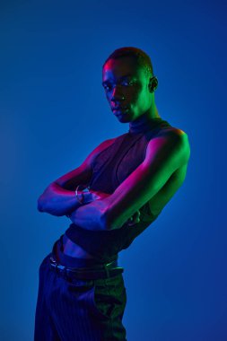 Genç bir Afrikalı Amerikalı, mavi ve yeşil tonlarında çapraz kollarıyla güven yayıyor..