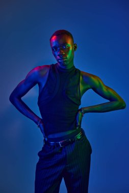 Genç bir Afrikalı Amerikalı şık giyinerek karizma yayıyor, parlak ışıklarla aydınlatılıyor..