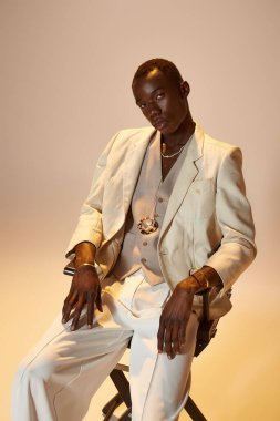 Genç bir Afro-Amerikan erkeği şık bir kıyafet içinde, kendine güveni ve tarzı ile poz veriyor..