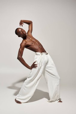 Afro-Amerikan bir gencin zarif pozu modaya uygun beyaz kıyafetli özgüven ve tarz sergiliyor.