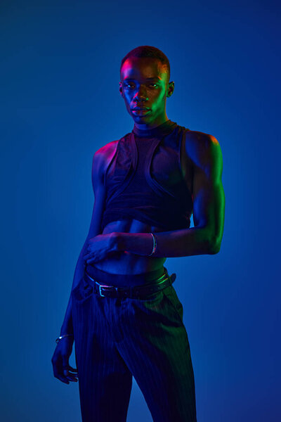 Молодой африканский американец демонстрирует свой стильный наряд с уверенностью среди яркого освещения.