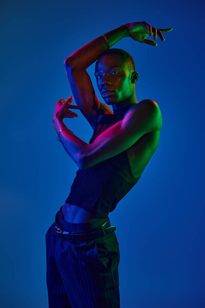 A young african american man shows off his style in a striking pose, surrounded by vibrant colors.
