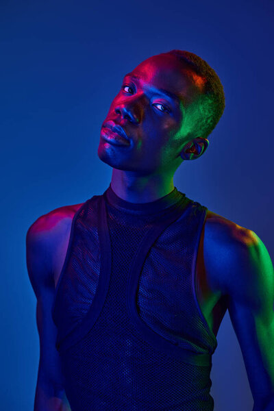 Молодой человек одевается в инновационный наряд, излучая уверенность на ярком красочном фоне.