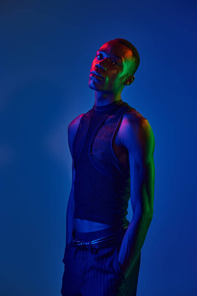 A confident young african american man shines in vibrant attire with striking lighting effects.