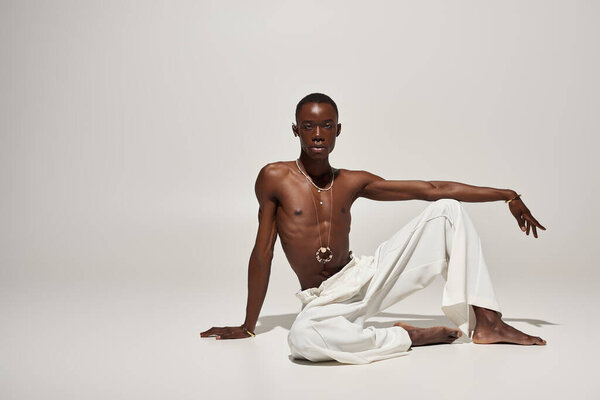 A young african american man dazzles in vibrant white attire, striking an attention grabbing pose.