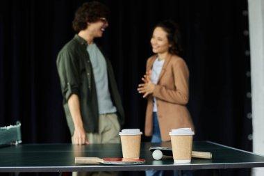 İki meslektaş, hareketli bir çalışma alanında kahve ve sohbet ederken hafif bir anın tadını çıkarırlar..