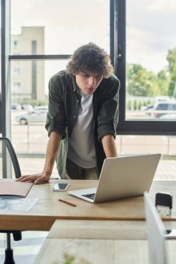 Çağdaş bir ofis ortamında dizüstü bilgisayarda özenle çalışan konsantre bireyler..