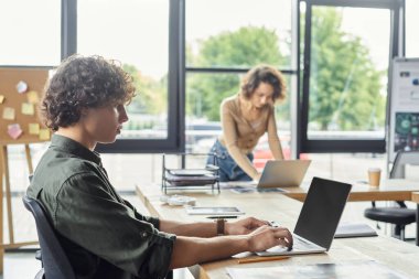 İki meslektaş, görevlerini yaparken parlak bir ofis alanında iş birliği yapıyorlar..