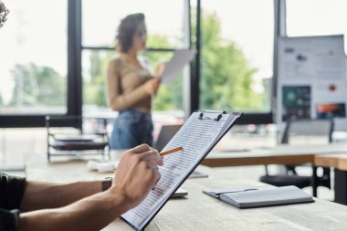 İnsanlar parlak bir ofiste birlikte çalışır, belgeleri gözden geçirir ve fikirleri paylaşırlar..