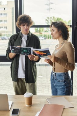 İki meslektaş modern bir ofiste proje materyalleri hakkında canlı sohbetler yapıyorlar..