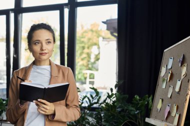 Profesyonel bir kadın, ilham dolu çalışma alanını gözlemlerken not alır..
