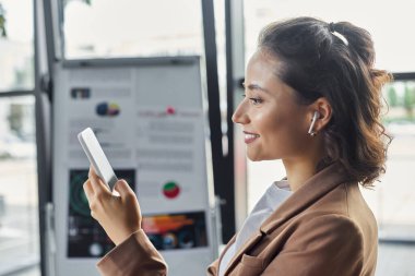 Kendini işine adamış biri şık, odaklı ofis ortamında akıllı telefon kullanır..