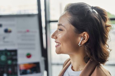 Parlak, modern bir ofis ortamında müzik dinlerken kendini işine adamış profesyonel bir gülümseme..