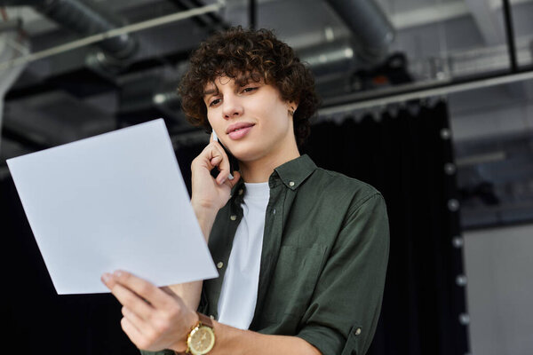 A young person talks on the phone while reviewing documents in an office.