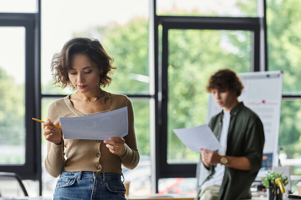 Двое коллег внимательно рассматривают документы, демонстрируют командную работу и преданность делу..