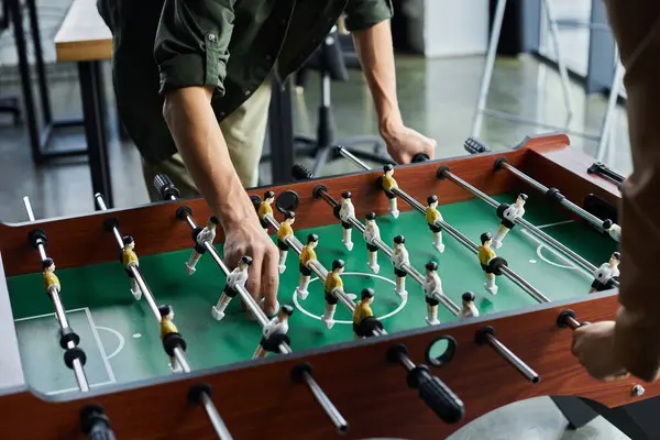 Colleagues enjoy a friendly game of foosball, showcasing teamwork and enjoyment during work hours.